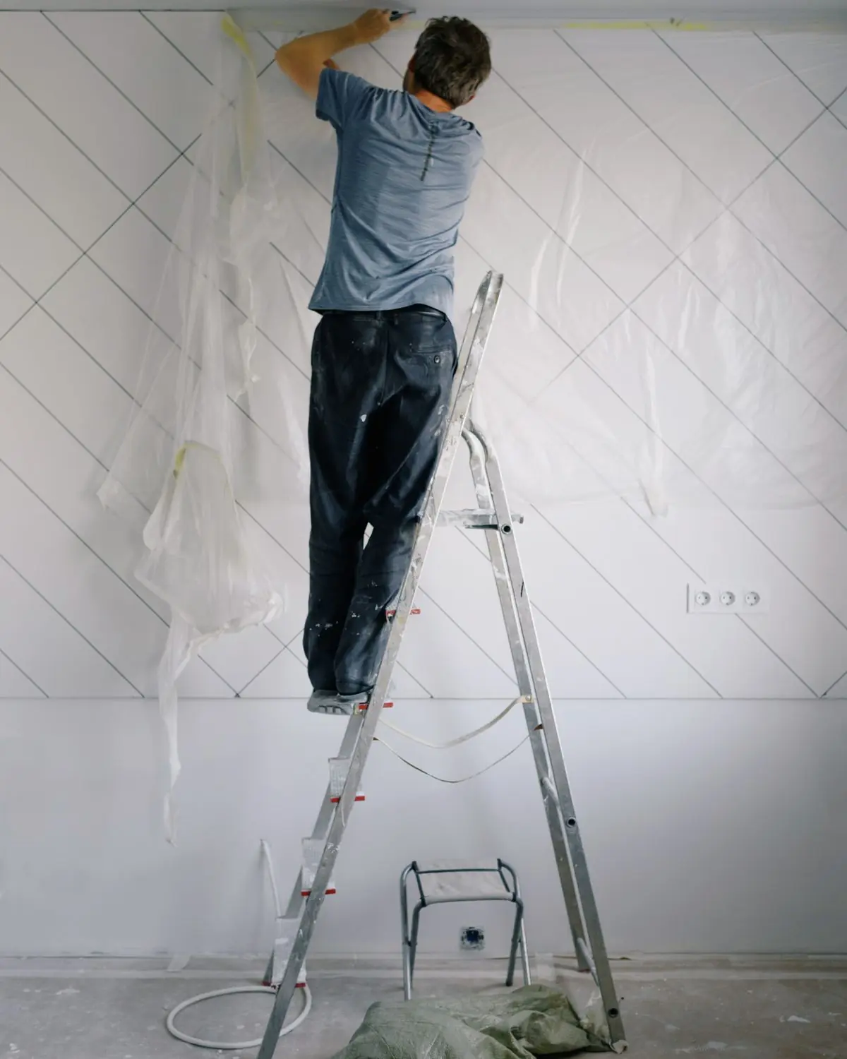 Plasterer on a step ladder finishing the top of a boarded wall