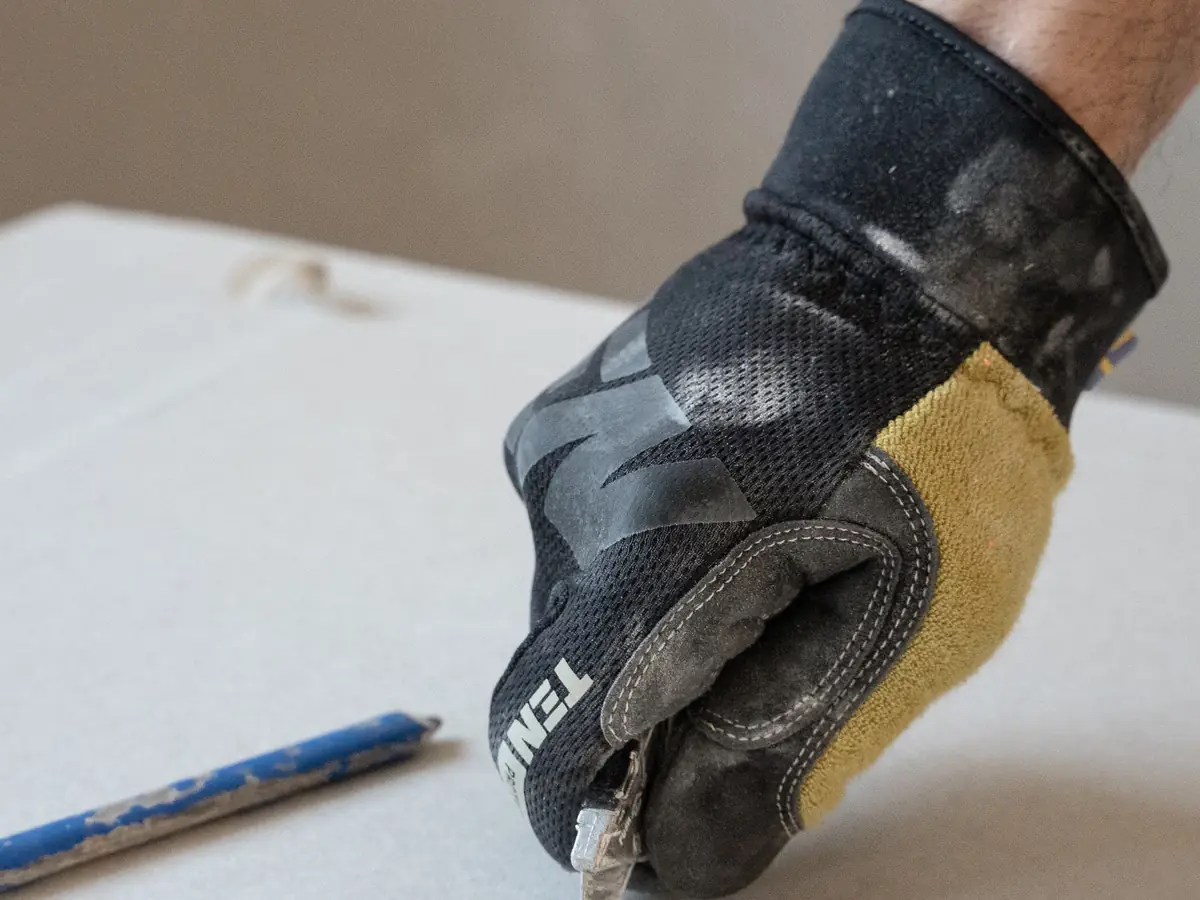 Cutting plasterboard to size with a knife and straight edge