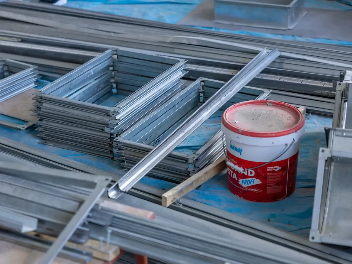 Stacked metal stud sections and a bucket of compound on a site floor