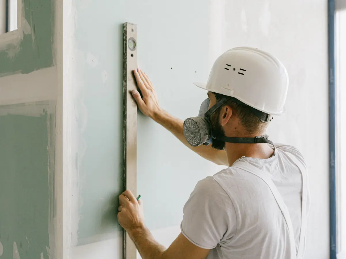 Checking a new stud wall for plumb with a long spirit level