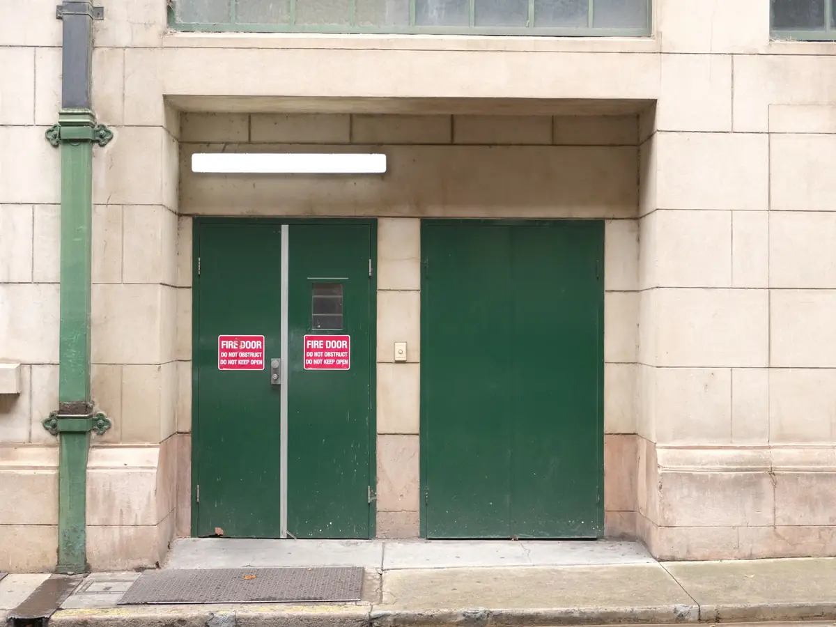 Green fire exit doors in a stone building with safety signage