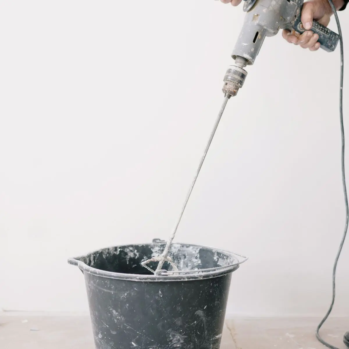 Mixing a bucket of plaster with a paddle mixer
