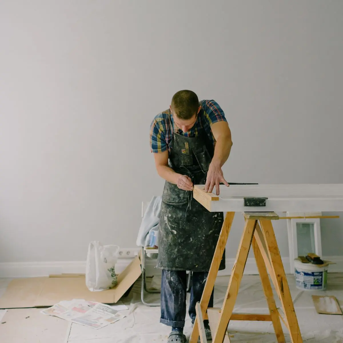 Cutting plasterboard on trestles inside a stripped room