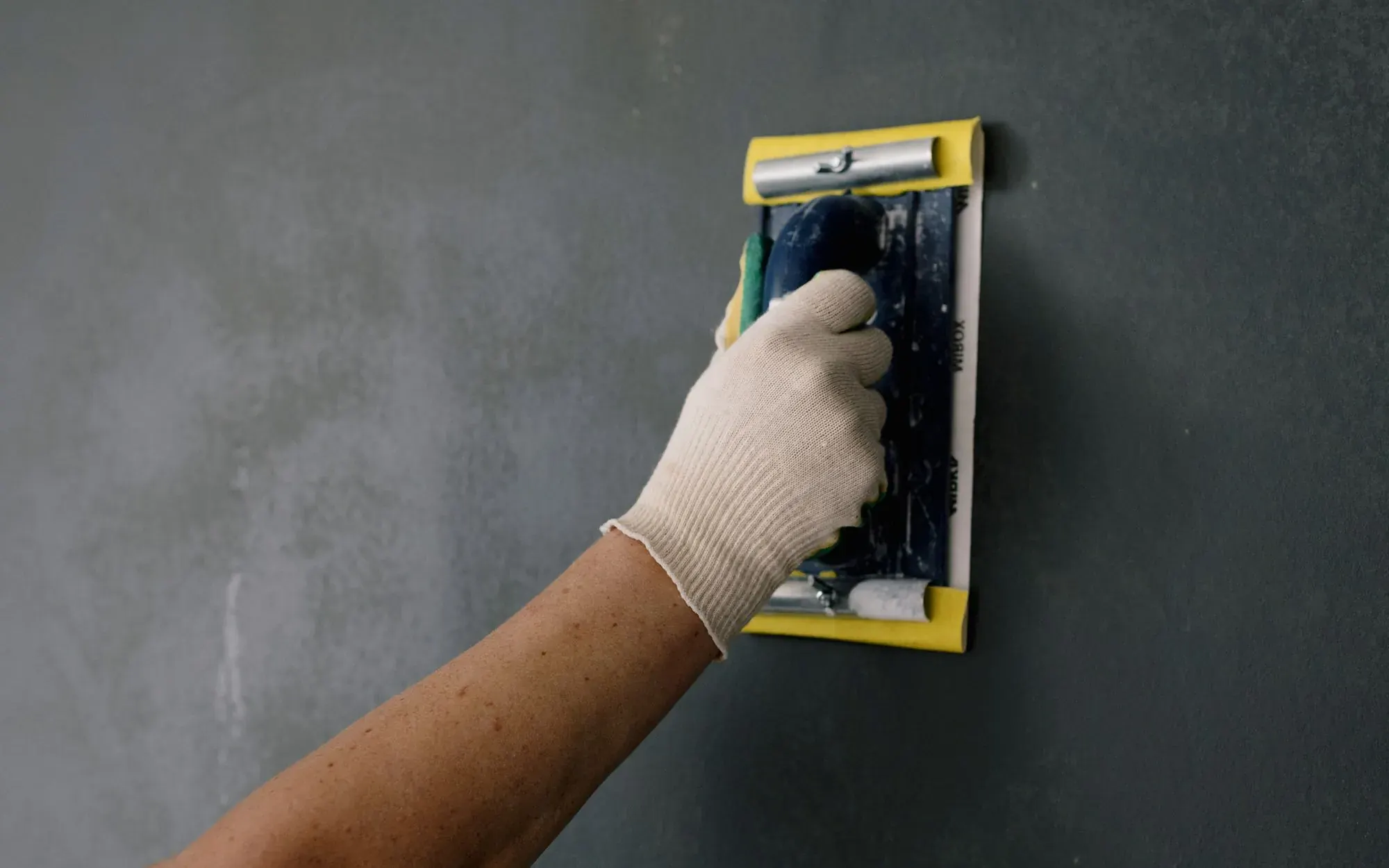 Plasterer working a float across a freshly rendered wall