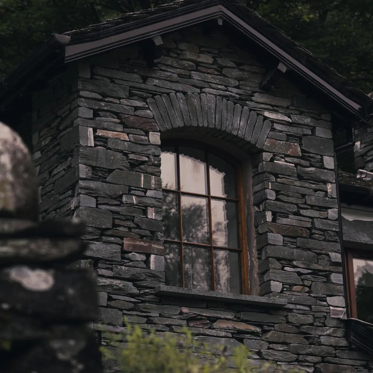 Old stone house wall with a timber window