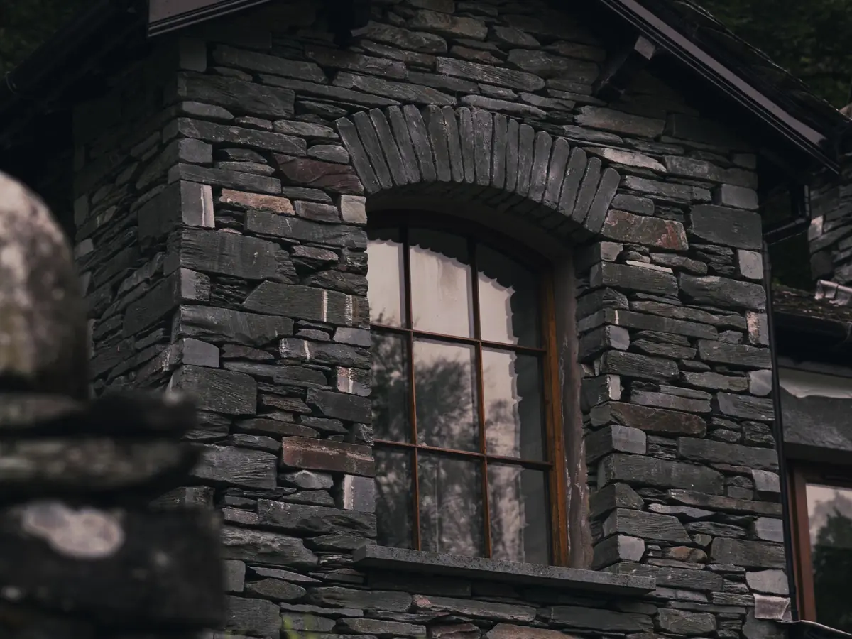 Old stone house wall with a timber window and slate detail