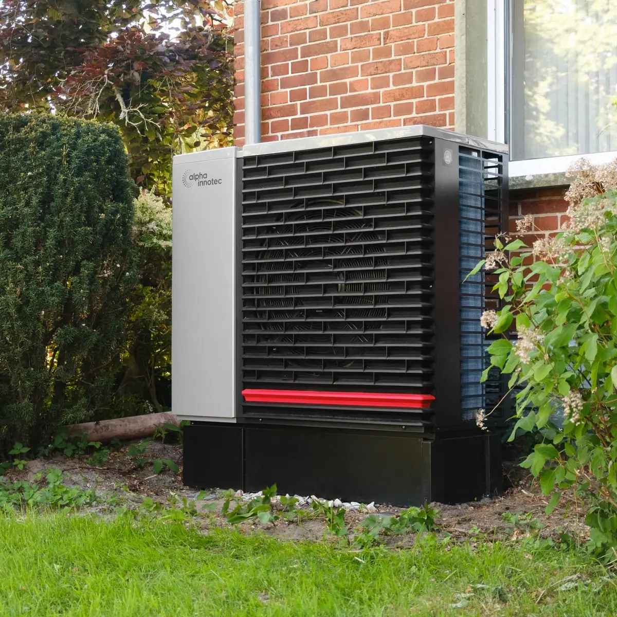 Air source heat pump unit in a garden beside a house