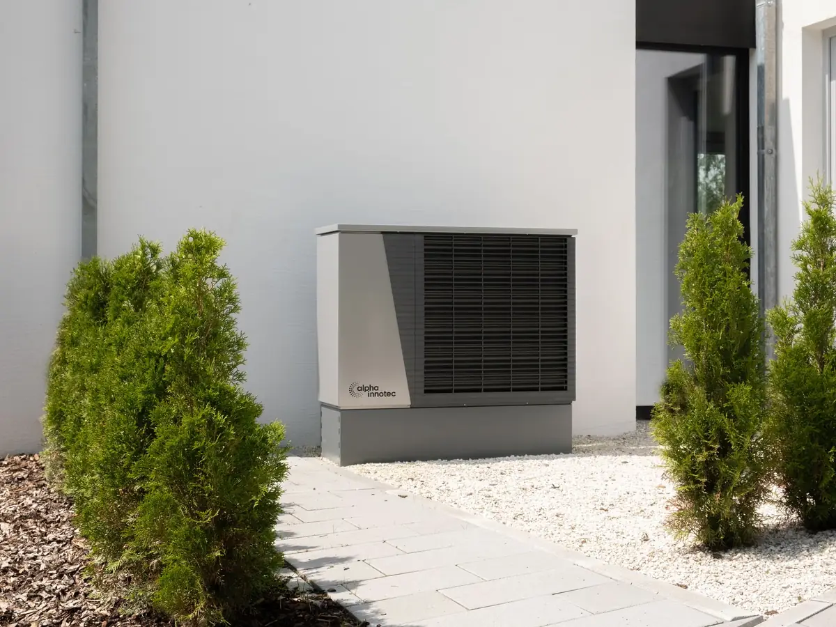 Heat pump unit outside a house with planting around it