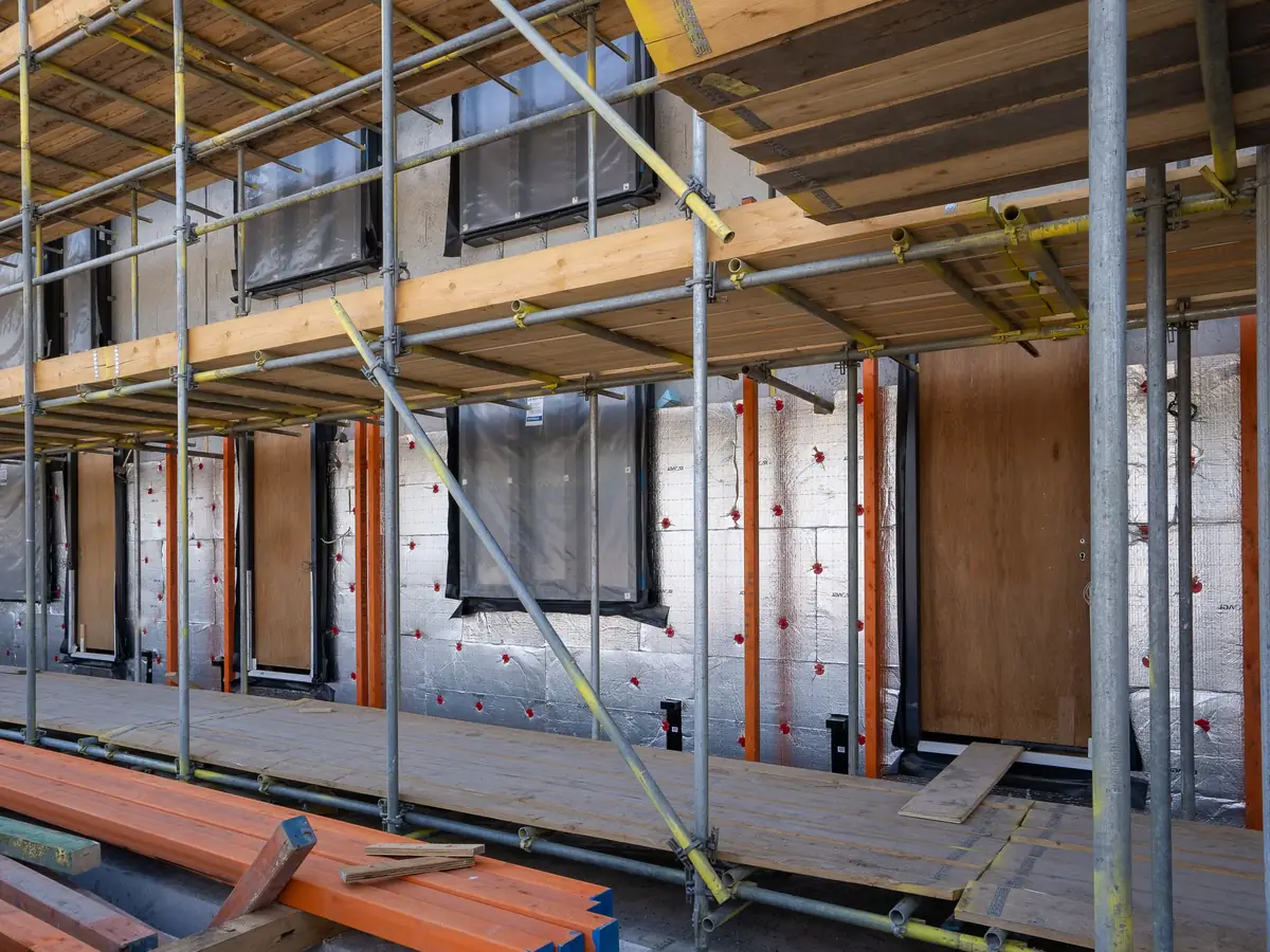Insulation boards fixed across a house wall behind scaffolding