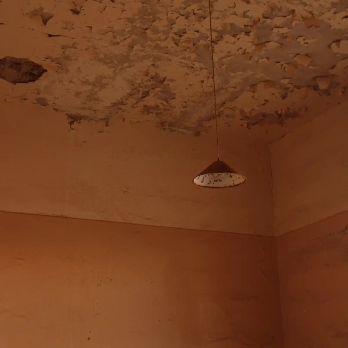 Old cracked ceiling beside a pendant light