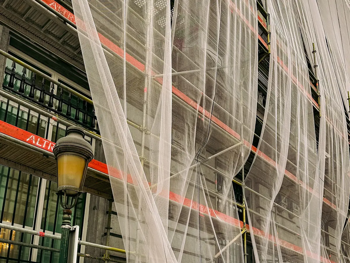 Scaffolding wrapped in mesh across a building front during rendering