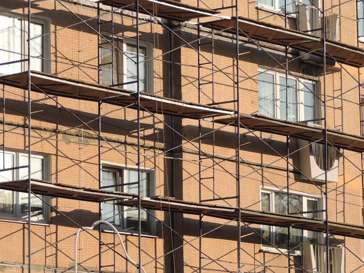 Scaffolding against a rendered building in bright sunlight