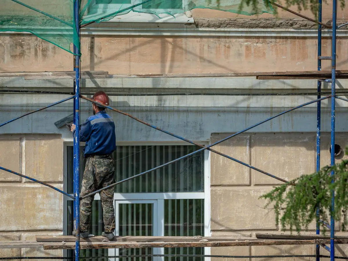 Renderer applying a coat from scaffolding
