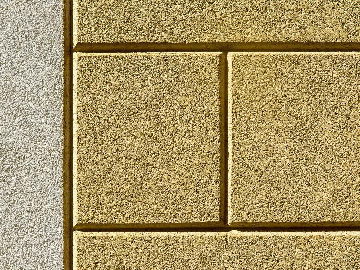 Warm ochre render with ashlar lines in low sunlight