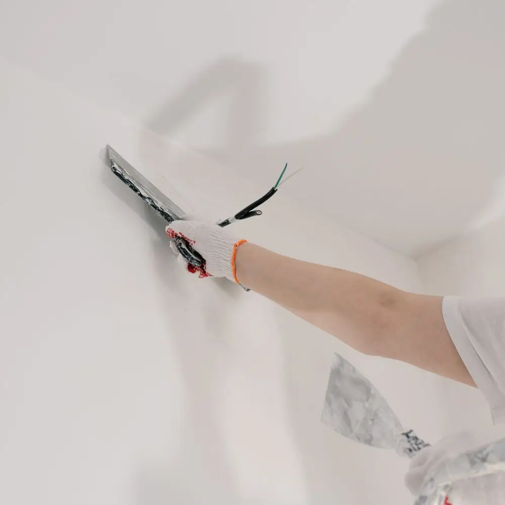 Trowel finishing the wall line beneath a ceiling