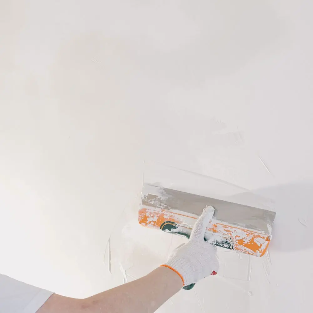 Plasterer skimming a wall with a stainless trowel