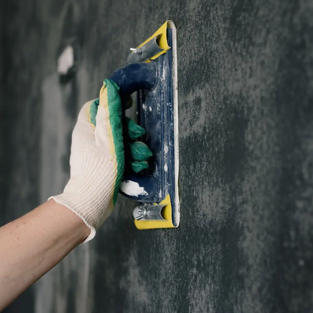 Float working a fresh base coat of render on an external wall