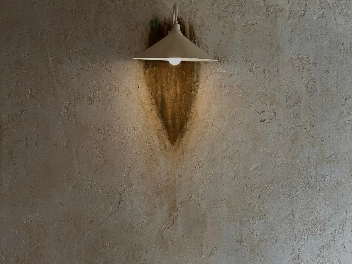 Wall lamp on a textured plaster wall in warm light