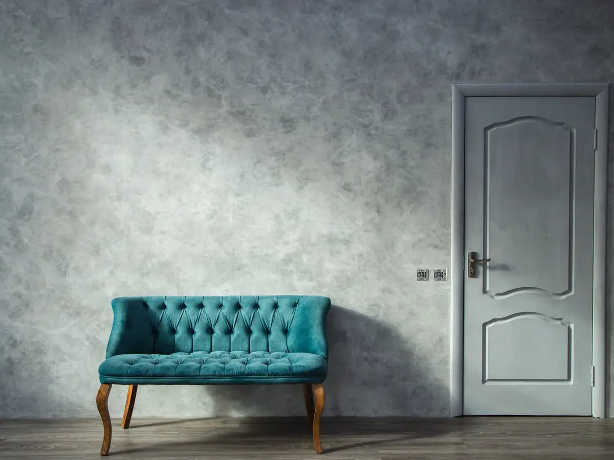 Teal velvet sofa against a soft grey polished plaster wall